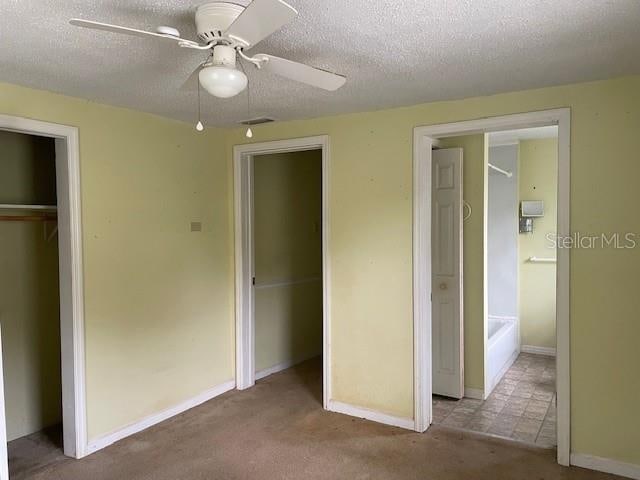 unfurnished bedroom featuring carpet floors, ceiling fan, and a textured ceiling