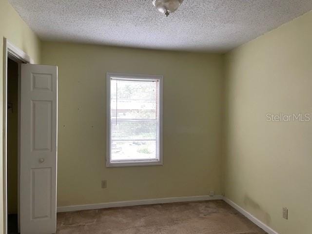 carpeted spare room featuring a textured ceiling