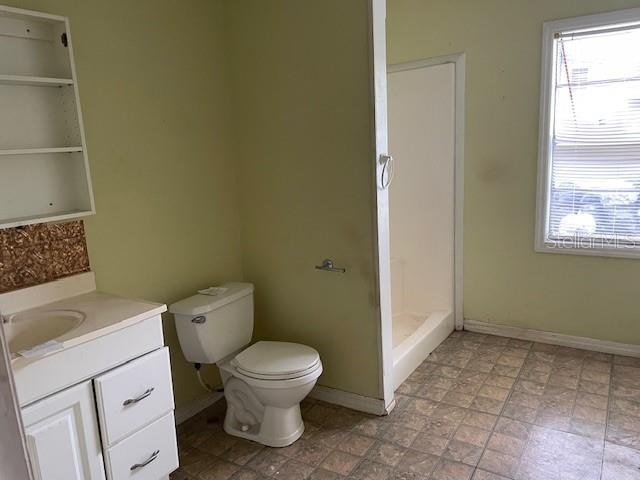 bathroom with vanity, tile flooring, a shower, and toilet