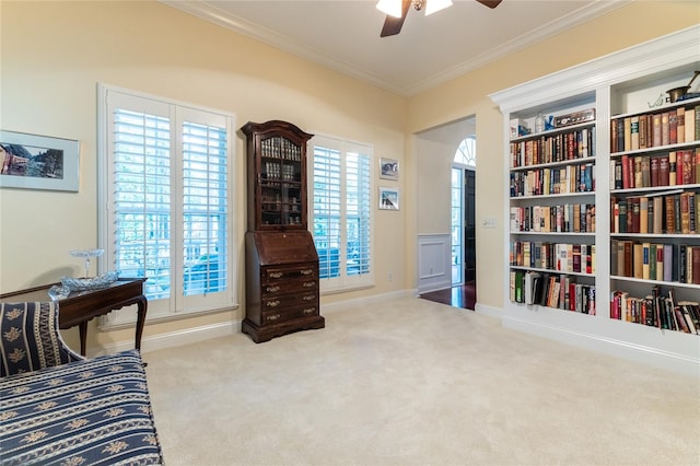 living area featuring crown molding, built in shelves, carpet, and ceiling fan