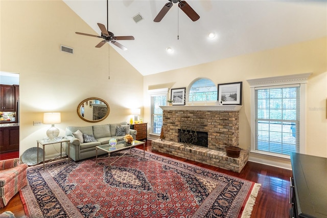 living room featuring high vaulted ceiling, dark wood-type flooring, ceiling fan, and a brick fireplace