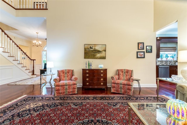 living room featuring a notable chandelier, crown molding, a towering ceiling, and hardwood / wood-style floors