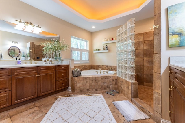 bathroom with tile flooring, tiled bath, vanity, and a raised ceiling