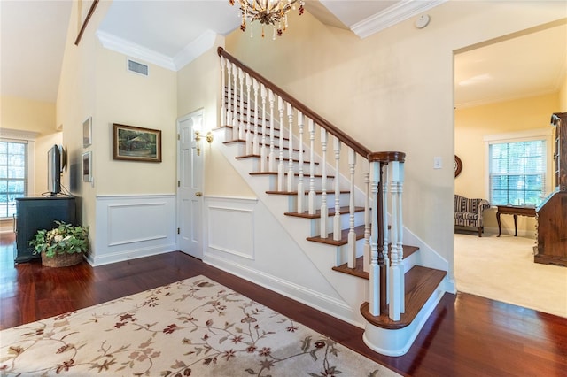 stairway with carpet flooring, plenty of natural light, ornamental molding, and a chandelier