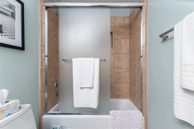 bathroom with combined bath / shower with glass door and toilet