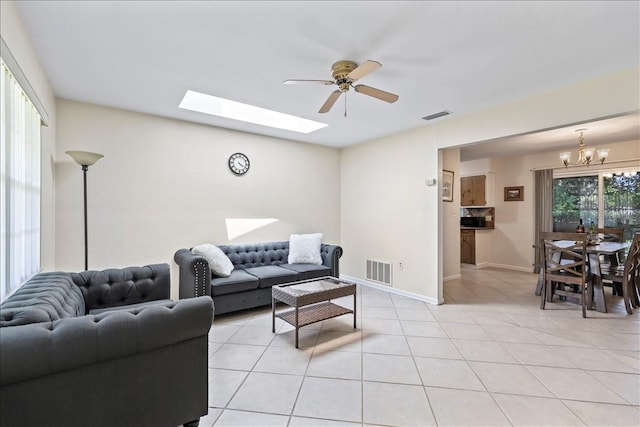 living room with light tile flooring, a skylight, and ceiling fan with notable chandelier