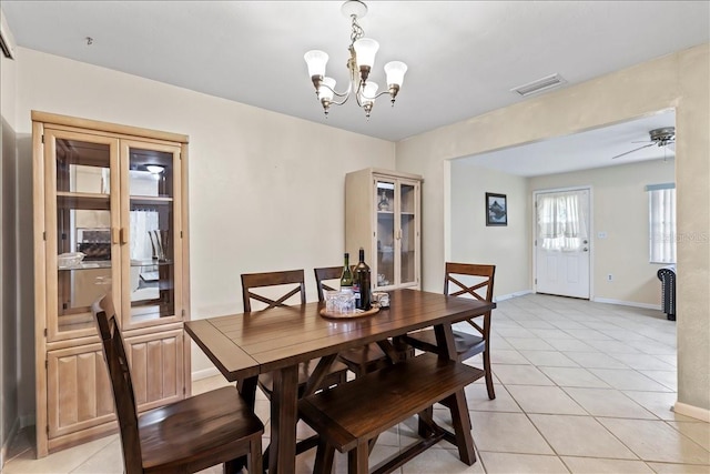 tiled dining room featuring ceiling fan with notable chandelier