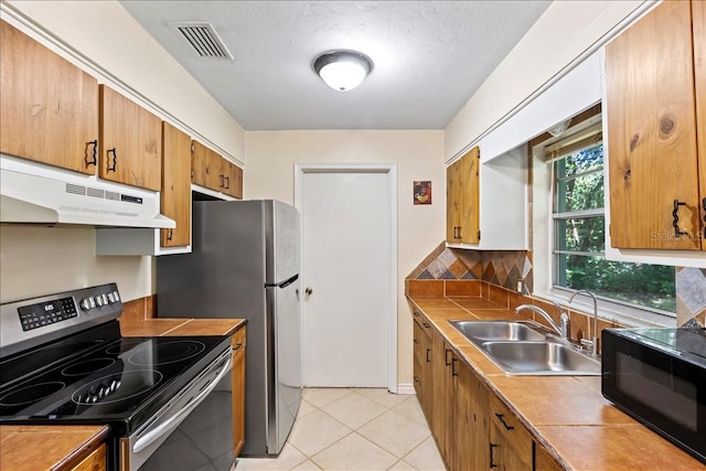 kitchen featuring appliances with stainless steel finishes, tile countertops, sink, and light tile flooring