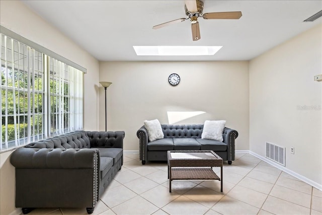 living room featuring light tile floors, a skylight, and ceiling fan