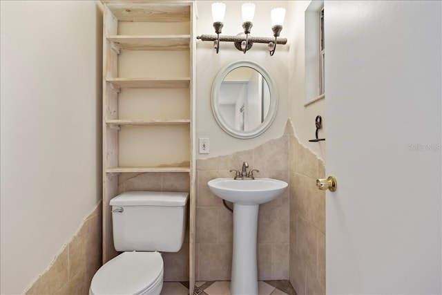 bathroom featuring tile floors, toilet, and tile walls