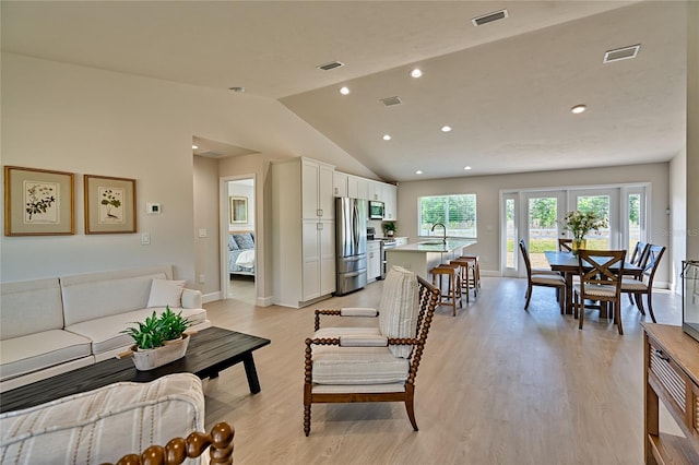 living room with lofted ceiling, light hardwood / wood-style floors, french doors, and sink