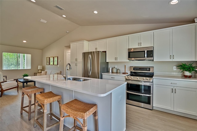 kitchen with light hardwood / wood-style floors, stainless steel appliances, vaulted ceiling, white cabinetry, and sink