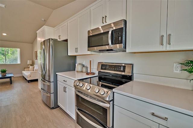 kitchen with light hardwood / wood-style flooring, stainless steel appliances, vaulted ceiling, and white cabinets