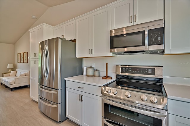 kitchen with lofted ceiling, stainless steel appliances, white cabinets, and light wood-type flooring