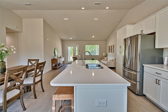 kitchen featuring white cabinetry, light wood-type flooring, a kitchen island with sink, lofted ceiling, and sink