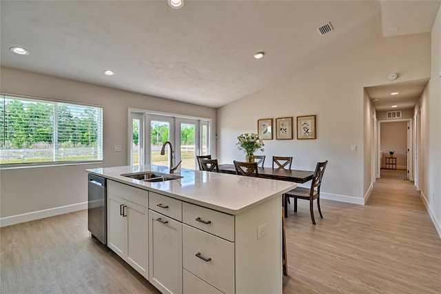 kitchen with lofted ceiling, sink, light wood-type flooring, an island with sink, and white cabinets