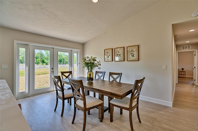 dining area featuring light hardwood / wood-style floors, vaulted ceiling, and a wealth of natural light