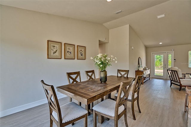 dining area featuring french doors, vaulted ceiling, and light wood-type flooring