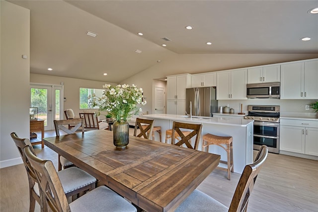 dining room featuring lofted ceiling, light hardwood / wood-style floors, and french doors