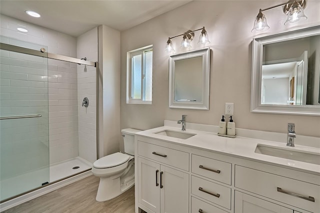 bathroom featuring an enclosed shower, double sink vanity, hardwood / wood-style flooring, and toilet