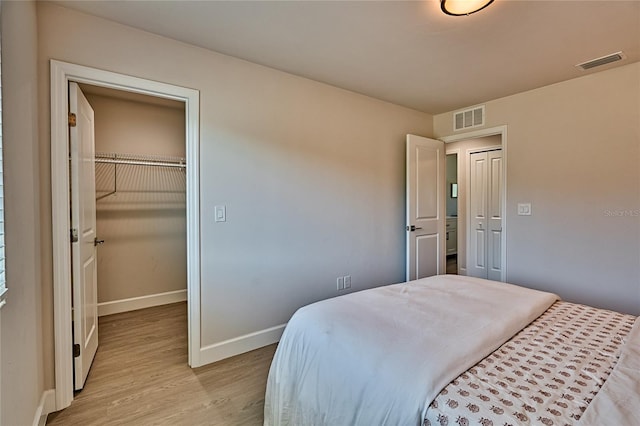 bedroom with a spacious closet, a closet, and light wood-type flooring