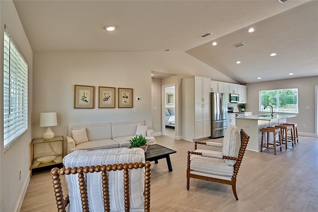 bedroom with sink, lofted ceiling, stainless steel refrigerator, and light hardwood / wood-style flooring