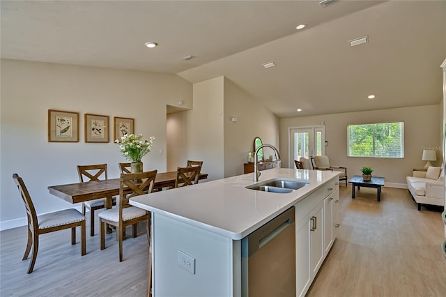 kitchen with an island with sink, vaulted ceiling, light hardwood / wood-style flooring, white cabinets, and sink