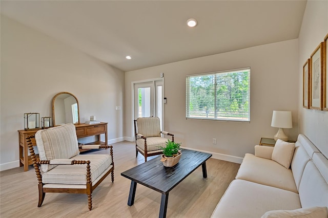 living room featuring lofted ceiling and light hardwood / wood-style floors