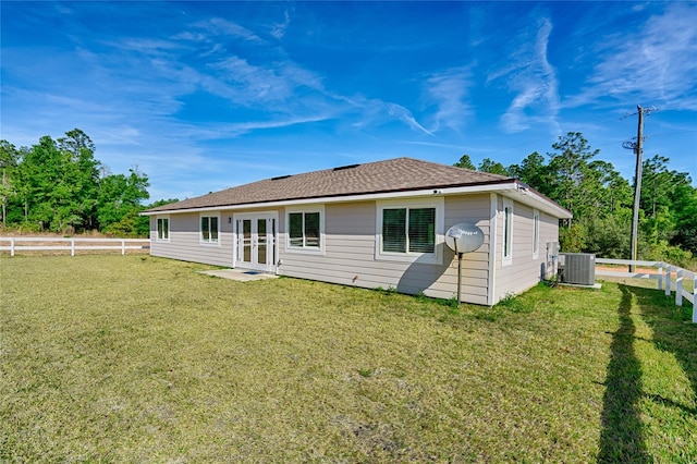 rear view of property featuring central AC and a lawn