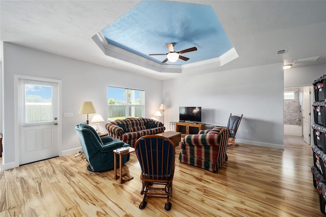 living room featuring ceiling fan, a tray ceiling, and light hardwood / wood-style floors