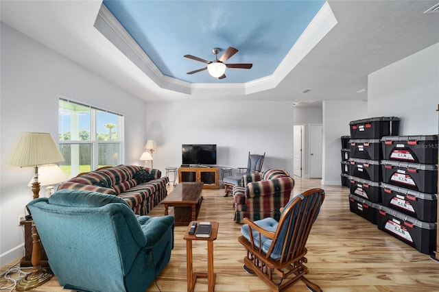 living room with ceiling fan, crown molding, a raised ceiling, and light hardwood / wood-style floors