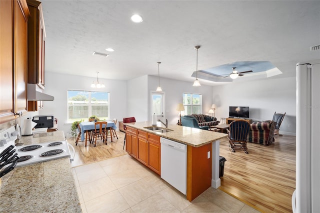 kitchen featuring wall chimney range hood, light hardwood / wood-style floors, plenty of natural light, and white appliances