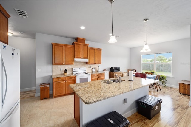 kitchen with light stone counters, pendant lighting, backsplash, white appliances, and sink