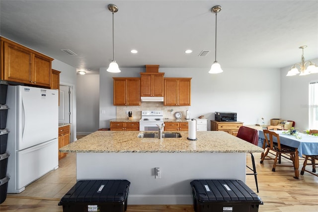 kitchen featuring white appliances, tasteful backsplash, a center island with sink, and decorative light fixtures