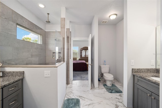 bathroom featuring toilet, a wealth of natural light, tile floors, and vanity with extensive cabinet space