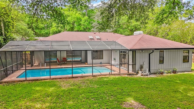 view of pool with glass enclosure, a lawn, and a patio area