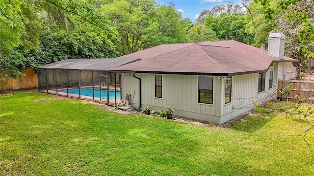 rear view of property with a fenced in pool and a lawn