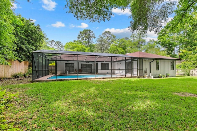 rear view of property featuring glass enclosure, a fenced in pool, and a lawn