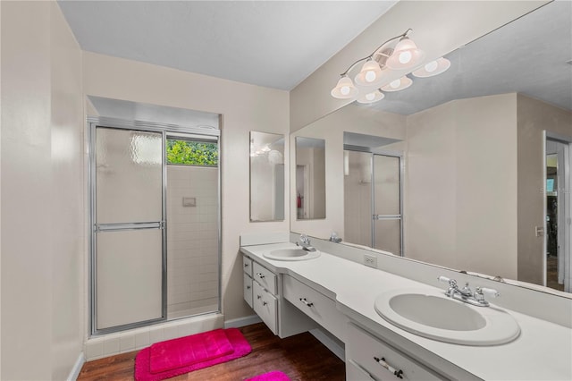 bathroom with oversized vanity, wood-type flooring, dual sinks, and a shower with shower door