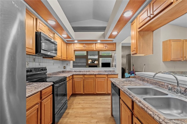 kitchen featuring tasteful backsplash, stainless steel appliances, light hardwood / wood-style flooring, sink, and vaulted ceiling