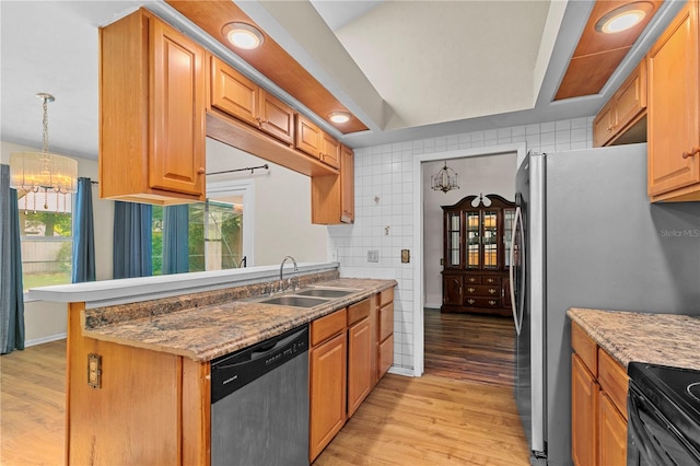 kitchen featuring dishwasher, decorative light fixtures, sink, backsplash, and light wood-type flooring