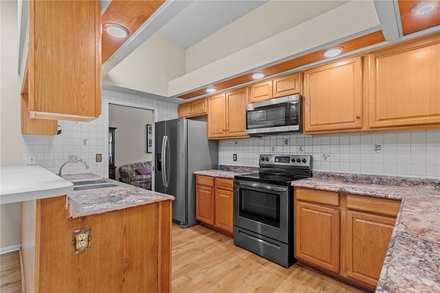 kitchen featuring sink, stainless steel appliances, light wood-type flooring, and tasteful backsplash