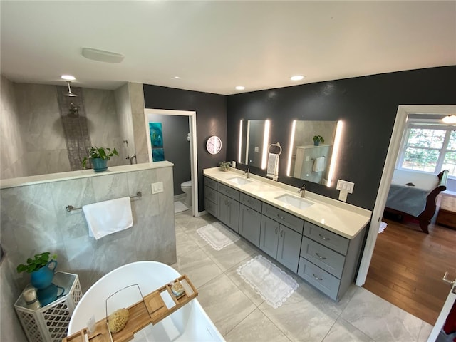 bathroom with toilet, tile patterned flooring, tiled shower, and vanity