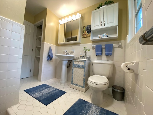 bathroom with toilet, tile walls, and tile patterned floors