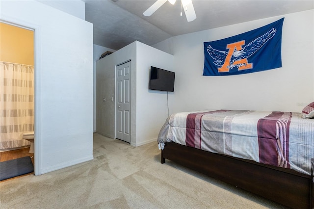 bedroom featuring a closet, ceiling fan, ensuite bath, light colored carpet, and vaulted ceiling