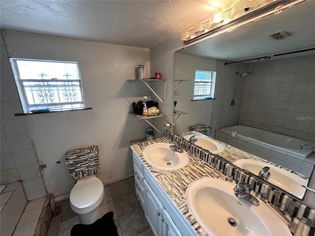 full bathroom featuring tile floors, tiled shower / bath, toilet, and dual bowl vanity