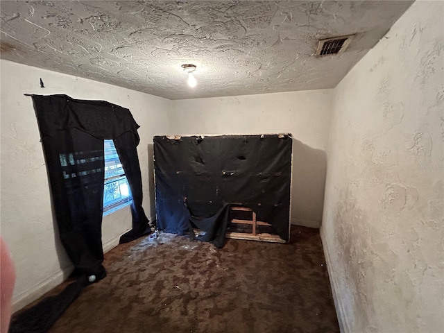 interior space with a textured ceiling and dark colored carpet