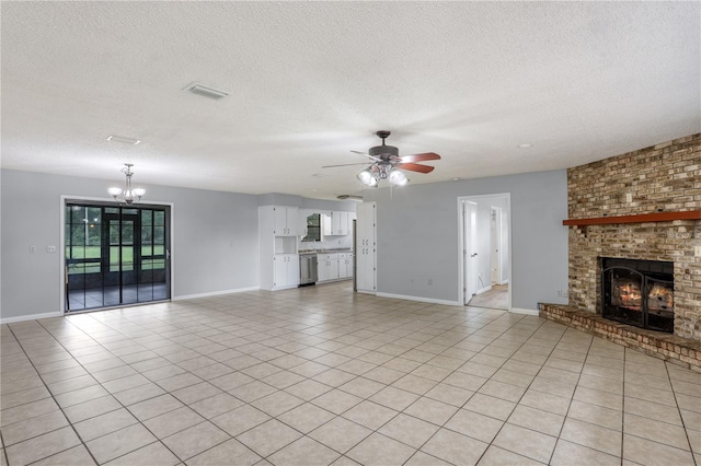 unfurnished living room featuring light tile patterned floors, a textured ceiling, ceiling fan with notable chandelier, visible vents, and a brick fireplace