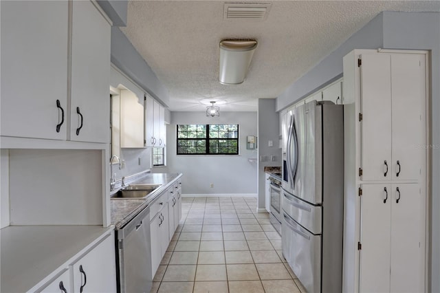 kitchen with visible vents, white cabinets, appliances with stainless steel finishes, a sink, and light tile patterned flooring