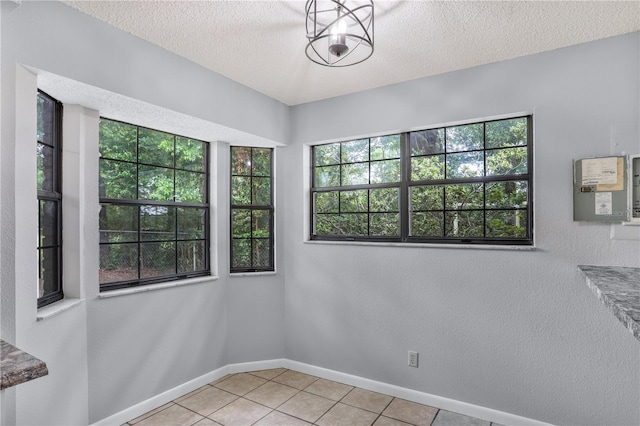 spare room with a textured ceiling, light tile patterned floors, and baseboards